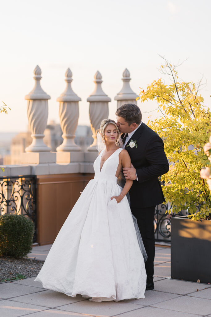 A bride and groom on the rooftop of The Brown Hotel during golden hour portraits right after their ceremony. The season is fall and the photos are true to life colors. 