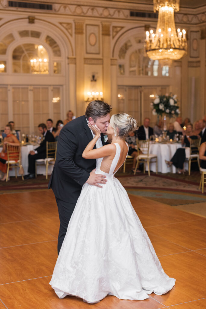 A bride and groom kissing at the end of their first dance in the middle of the ballroom at The Brown Hotel
