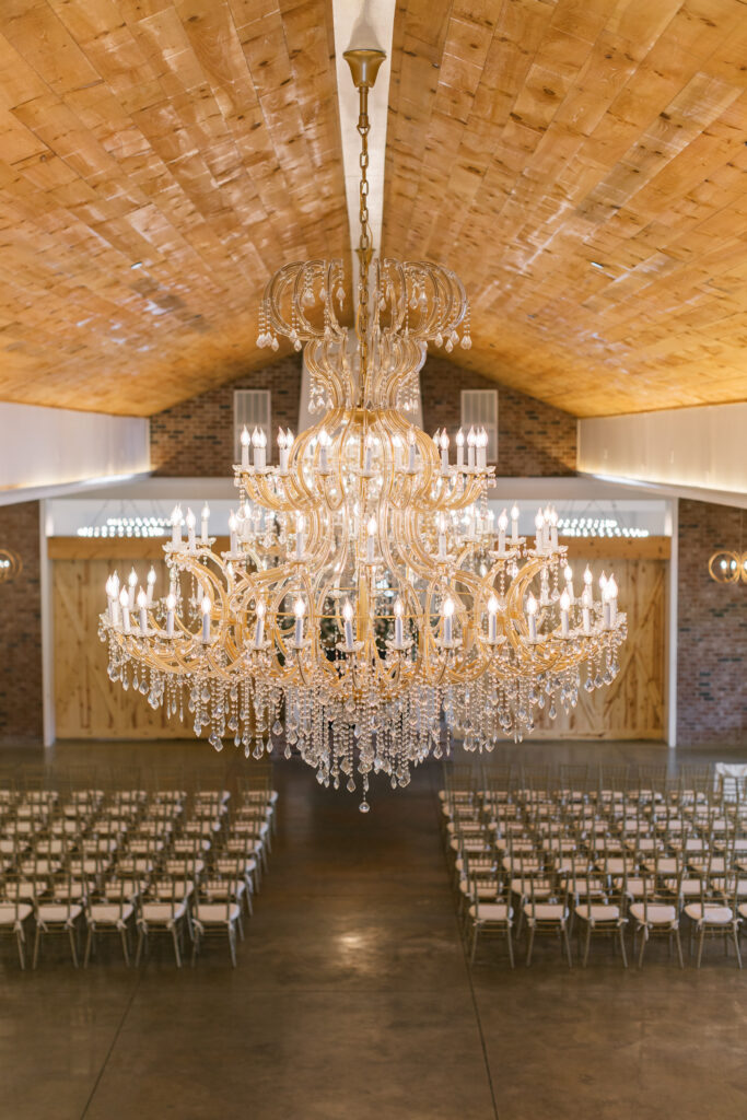 A photo of the ballroom at Hazelnut Farm taken from the top balcony. The photo focuses on the chandlers and the warmth of the room before guest arrive. 