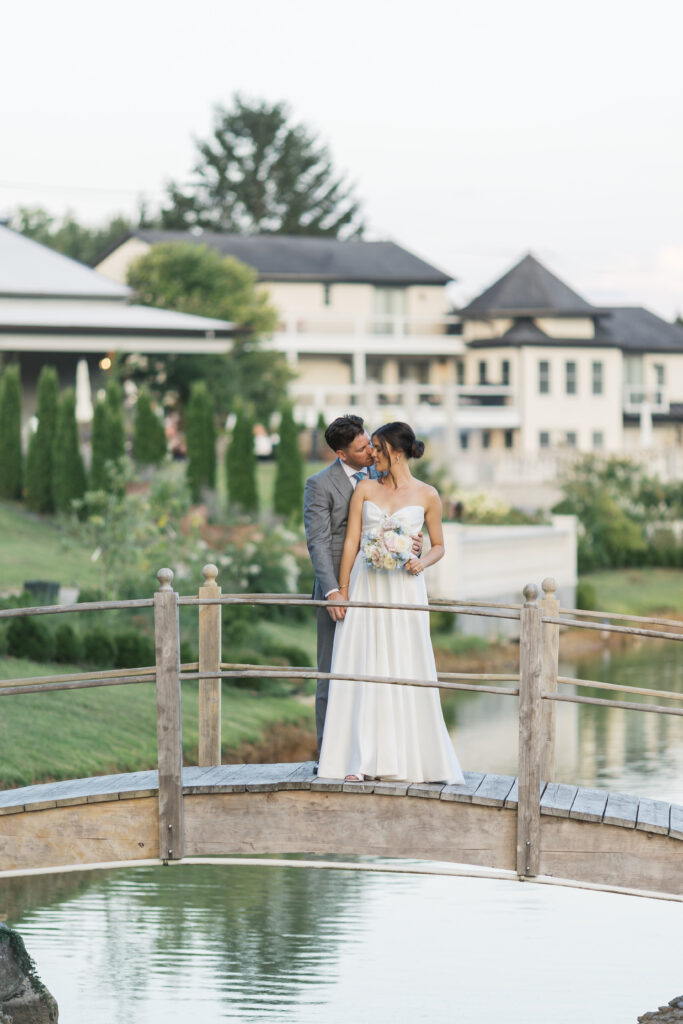 A bride and groom in a candid moment after the ceremony during golden hour. The couple is on the bride at Hazlenut farm with the estate in the background as guest enjoy cocktail hour. 